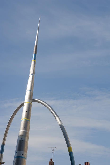 Alliance sculpture in Cardiff, Wales with a stainless steel pointed arrow column and hoop against a blue sky
