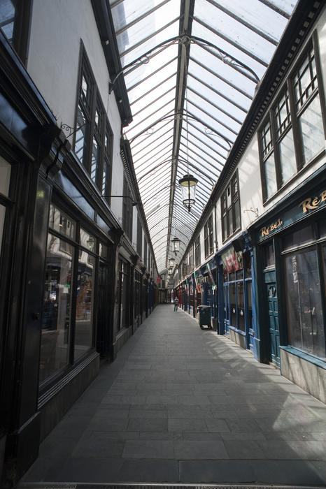 Interior of the Wyndham Arcade, a Victorian shopping arcade in Cardiff, Wales which is enclosed by a glass roof over the store fronts