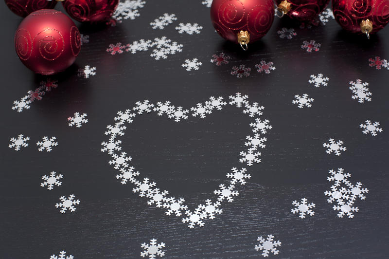 Christmas snowflake heart decoration on a dark background with colourful red bauble ornaments