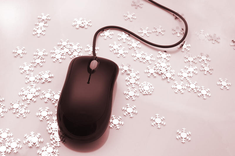 Computer mouse surrounded by scattered ornamental snowflakes conceptual of Christmas online shopping