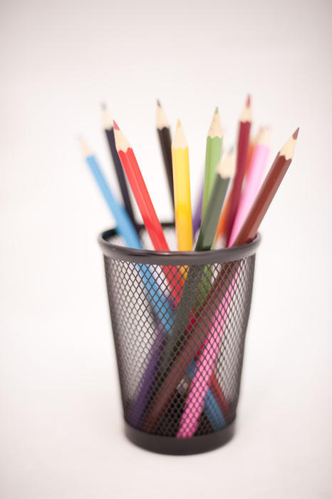 Coloured office pencils standing upright in a small metal container ready for use