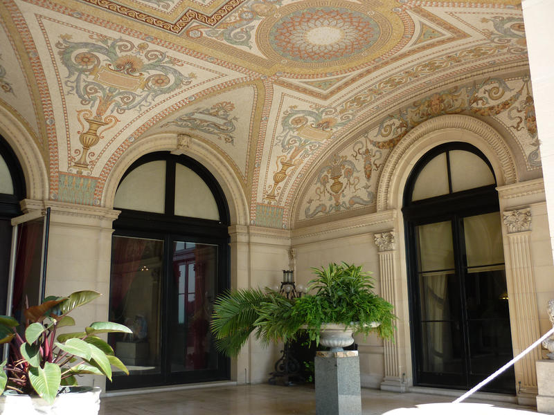 Decorative mosaic ceiling with a classical inlaid pattern in muted pastel colours in a vestibule or atrium inside a building with arched doorways