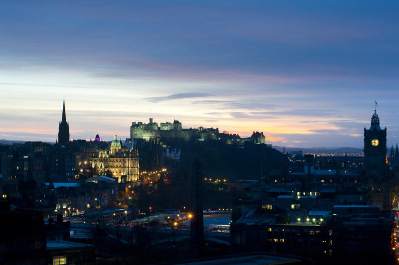 View across the illuminated city of the floodlit Edinburgh Castle and Rock at night