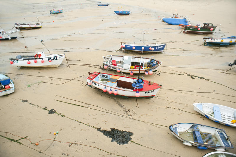 Boats beached on the sand by the receding tide at St Ives, Cornwall, a fishing town and resort