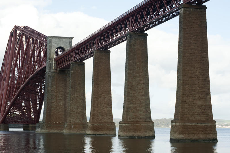 View from water level of the supports and approach viaduct of the Forth Rail Bridge as it crosses the Firth of Forth in Scotland near Edinburgh