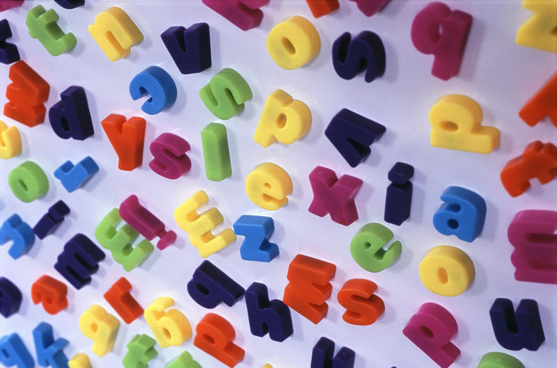 Scattered fridge magnet letters representational of the incomprehensible words seen by a person suffering from dyslexia with the word DYSLEXIA in the centre