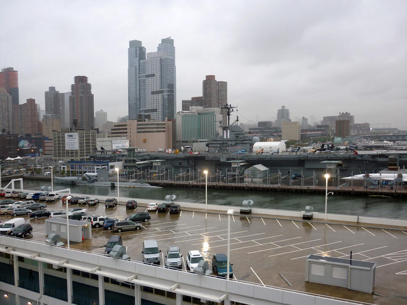View across rooftop parking to the cityscape of Manhattan on the skyilne under a grey cloudy wet sky