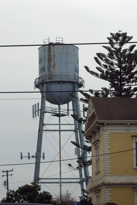 metal water tower stands high over the town of guadalupe, california