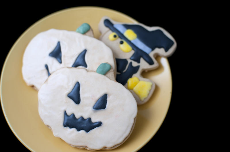 a place of halloween cookies decorated as a witch and pumpkins with icing