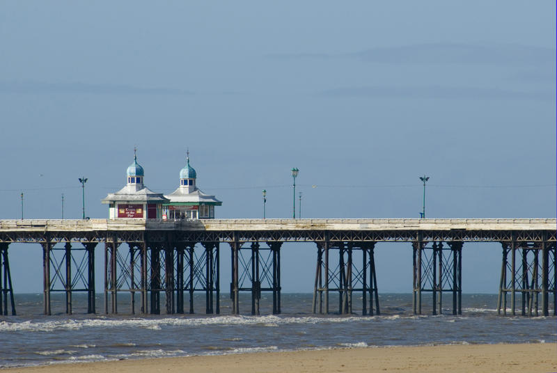 Blackpool North Pier with two quaint Victorian kiosks now housing small shops against a sunny blue sky
