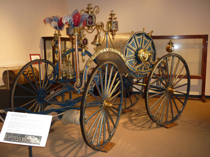 Beautiful nostalgic old historic horse-drawn fire wagon with brass coachwork and bell and a large reel mounted hose