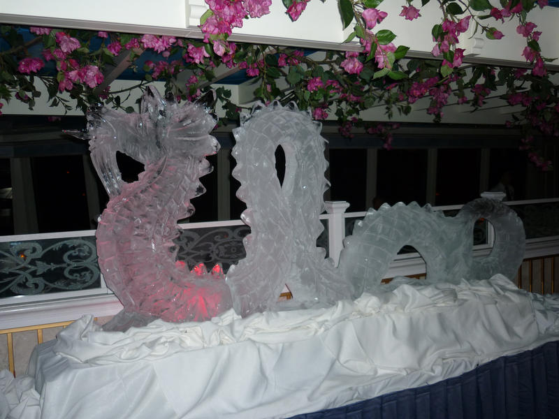 Sinuous ornately carved ice dragon sculpture on display surrounded by pink flowers