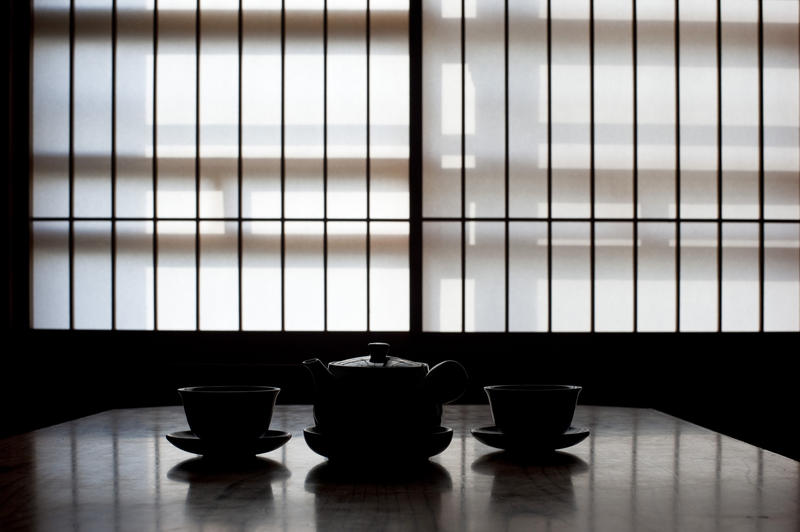 a tradational japanese paper window and silhouette tea service in the foreground