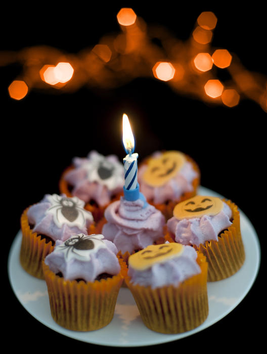 a plate with decorated halloween cakes and a candle burning