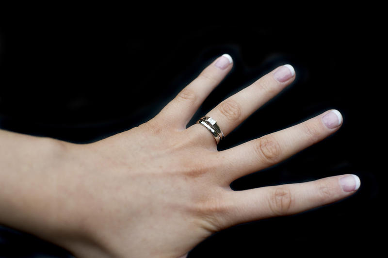 a lady wearing wedding and engagement rings on her ring finger