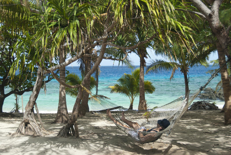 Lazy day on a summer vacation relaxing in a hammock slung between palm trees on an idyllic tropical beach