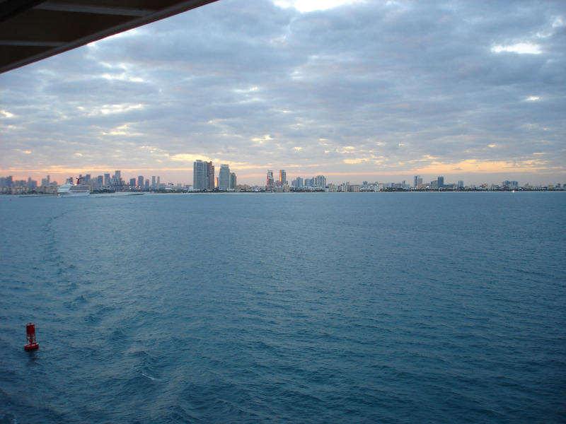 View from the deck of a luxury ship leaving Miami on a cruise of the cityscape on the horizon over open ocean