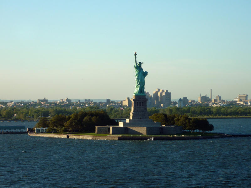 View from the ocean of the iconic Statue of Liberty on her small island against a clear blue sky, a gift from the French to the Americans