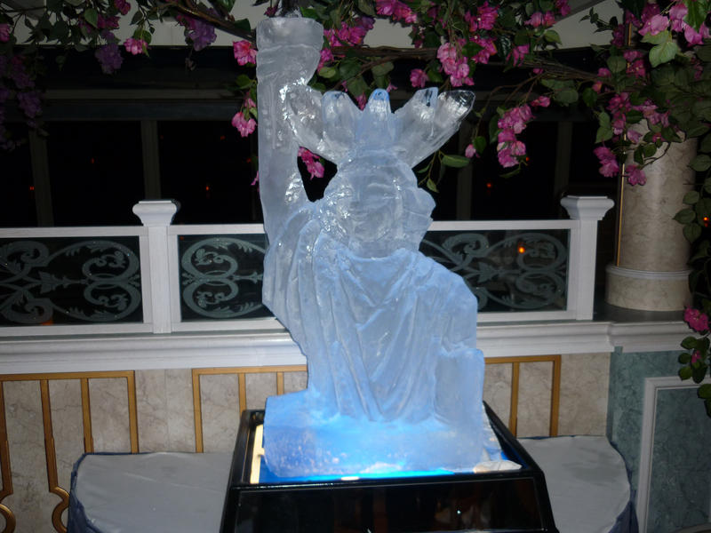 A bottom lit ice sculpture of the Statue of Liberty, with blue lighting