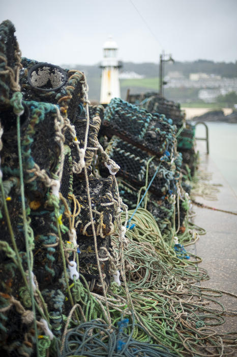 Closeup of lobster pots or lobster traps constructed of wire and wood stacked on the shore with their attached ropes and drag lines
