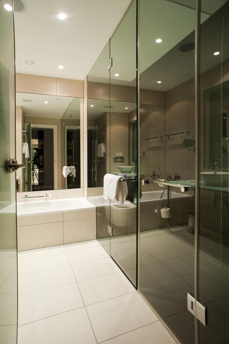 Looking through the door into the Interior of a modern residential bathroom with glass and tile decor