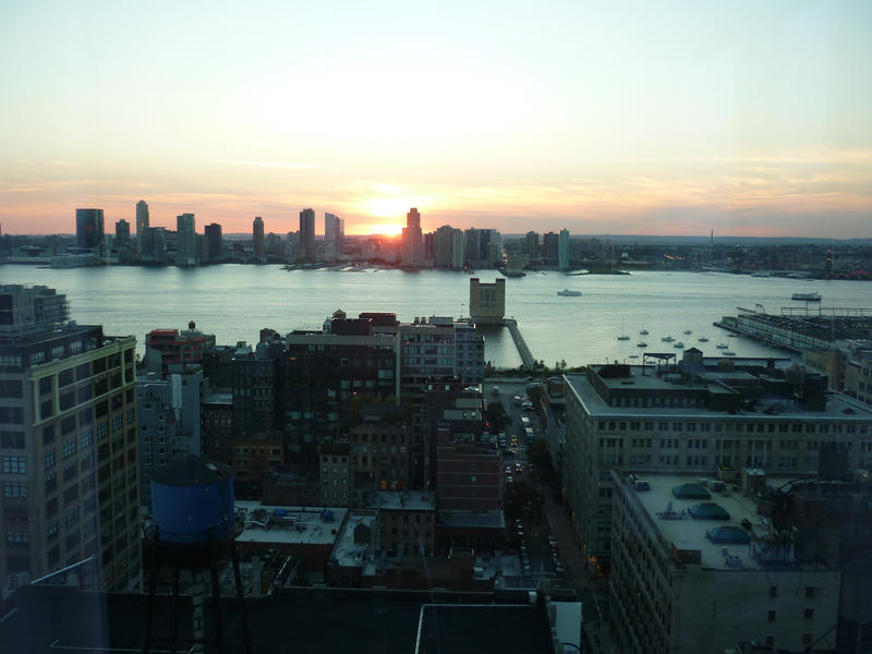 View over the East River of a glowing colourful sunset over New York with the skyscrapers silhouetted against the sky