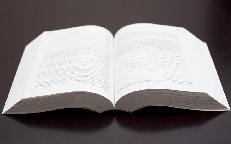 A studio shot of an open paperback book over a black background