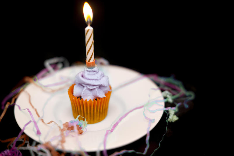 concept image, a single cake with one lone candle in it and streamers