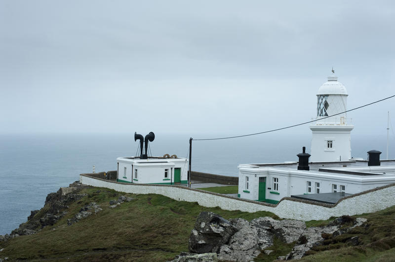 Pendeen Lighthouse, Cornwall sitting high above the ocean on a clifftop to warn shipping of the coastal hazard with a large foghorn in the forecourt for use in foggy weather