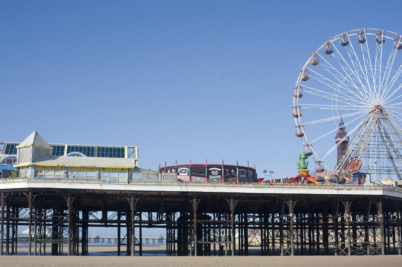 View across the beach of Blackpool Central Pier with its funfair and ferris wheel on a bright sunny day, Lancashire, England