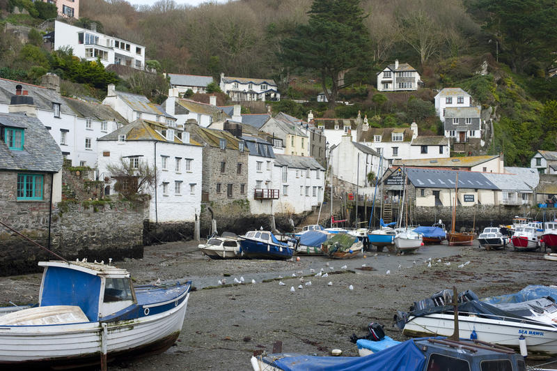 Looking from the sea at low tide to the fishing boats and traditional fishing village of Polperro in Cornwall, UK