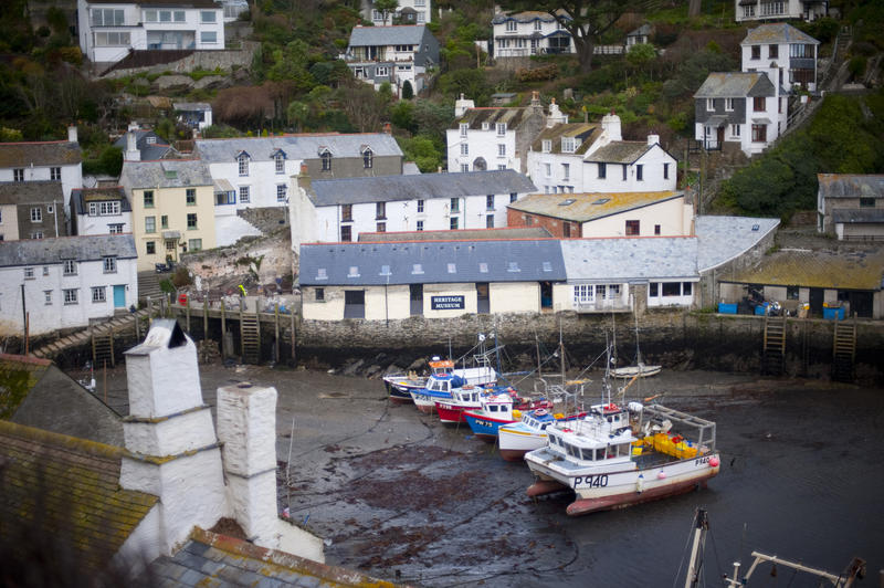 Polperro Fishing Village, Cornwall with its quaint white washed cottages and harbour with fishing boats beached on the sand at low tide