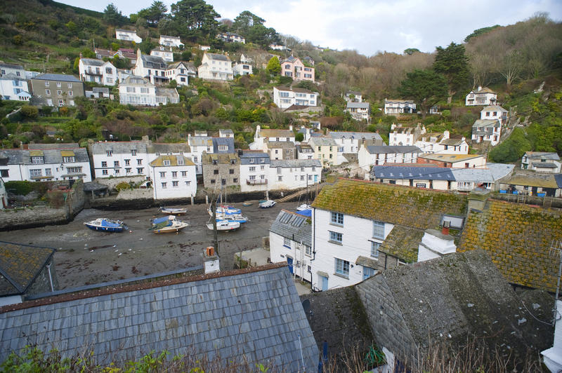 View of the quaint white-washed fishermans cottages spread across the hillside above the harbour in Polperro , Cornwall, a popular tourist attraction