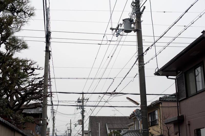 a common sight in japan, power and communications cables strung down the street from poles