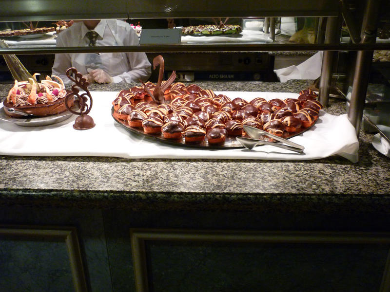 Display of chocolate covered profiteroles in a glass counter in a bakery