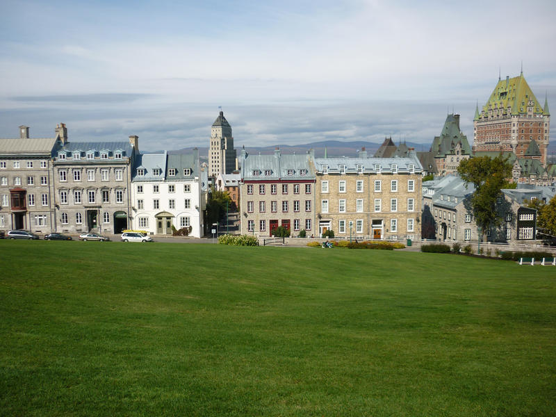 View across a green field towards Quebec city skyline showing the traditional quaint multistorey terraced buildings