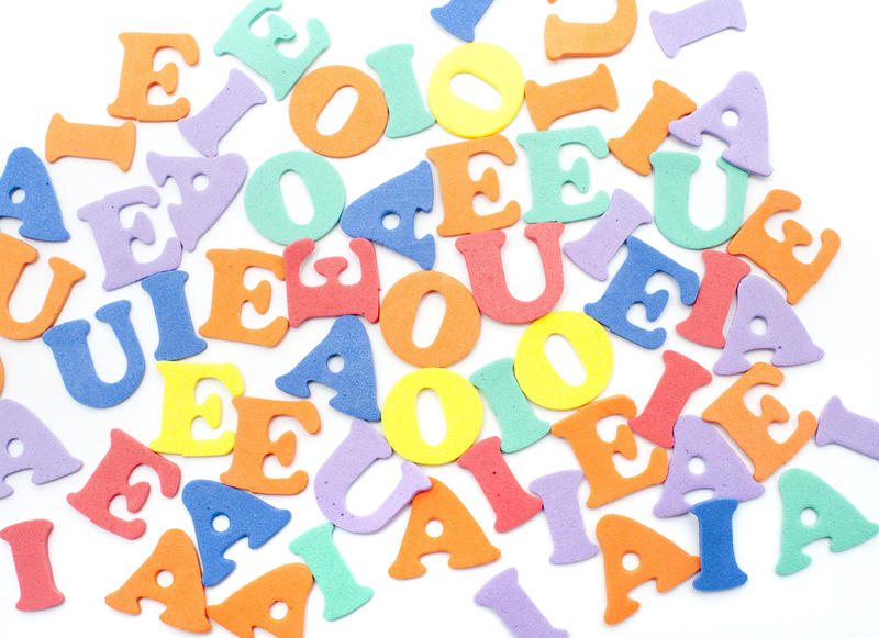 Colourful background of random vowels scattered on a white surface for teaching children to write, read and spell