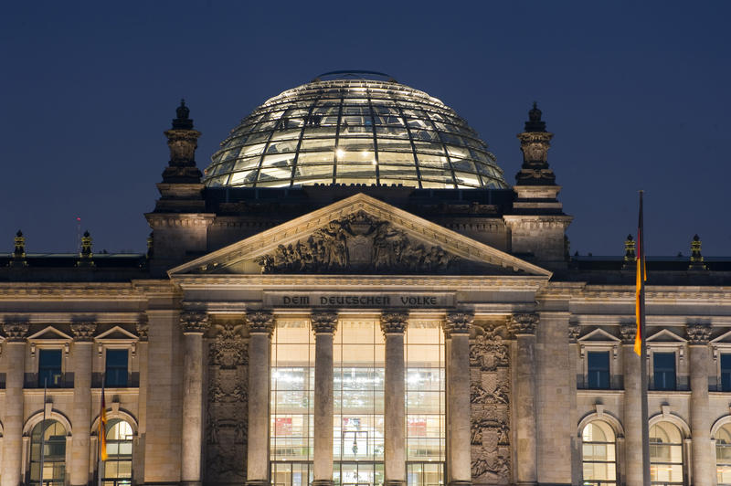 The Reichstag building, Berlin, the seat of the German parliament, illuminated at night with the glass dome that replaced the original cupola and the dedication to the people on the architrave