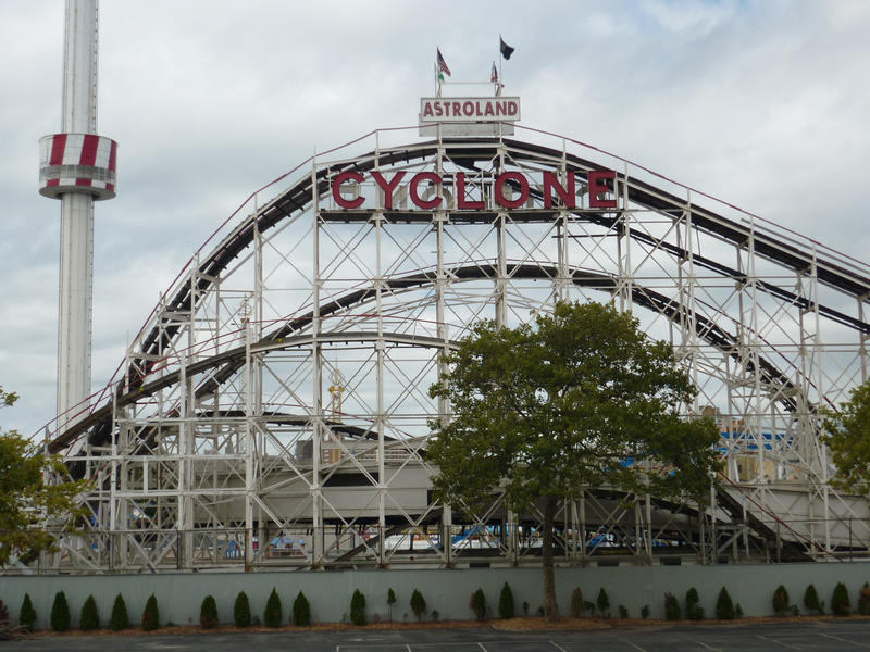 Steel framework of the Cyclone rollercoaster ride at Astroland amusement park silhouetted against a cloudy blue sky