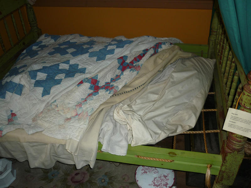 Small restored wooden antique country bed with rope supports for the bedclothes to lie on