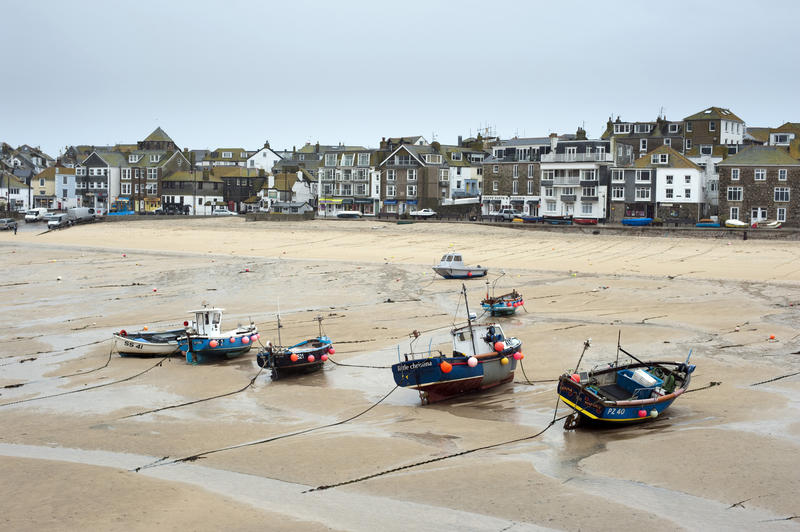 Fishing boats at St Ives beached high and dry on the sand at low tide overlooked by waterfront houses