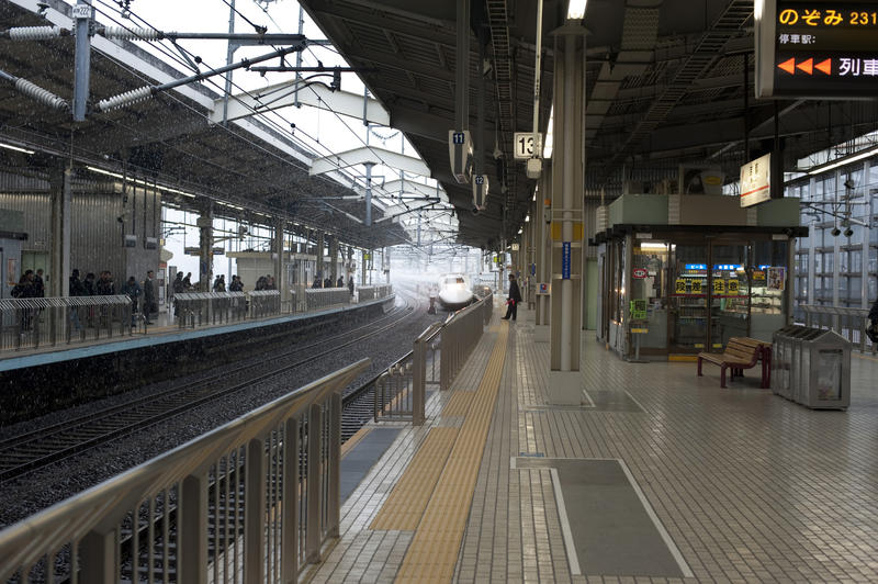 a shinkansen bullet train approaching a japanese railway station