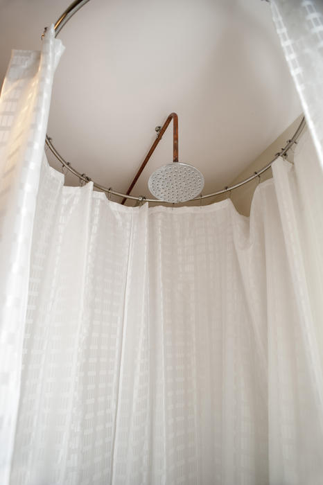 Low angle view looking up of a compact round shower cubicle with curtains on a circular rail and a metal shower head
