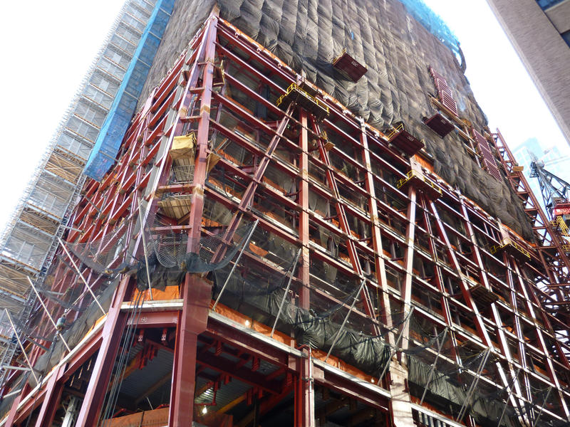 Detail of the construction of a skyscraper, showing the iron girder frame and scaffolding, taken from street level and looking up