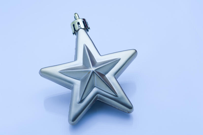 A single blue Christmas star decoration centred on a light blue background