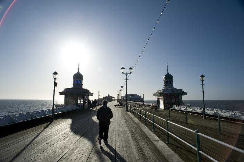 People walking along the promenade on Blackpool North Pier on a beautiful sunny day with clear blue sky