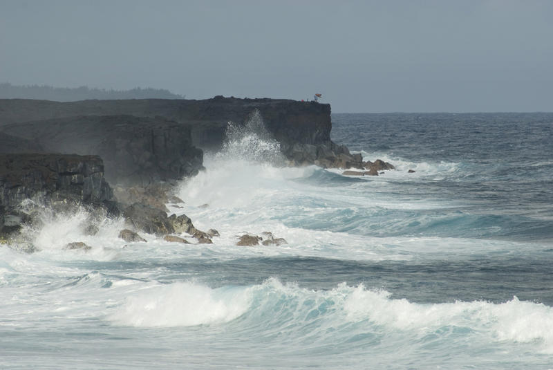 waves crashing against black volcanic rock cliff face at Kalapana, Big Island, Hawaii