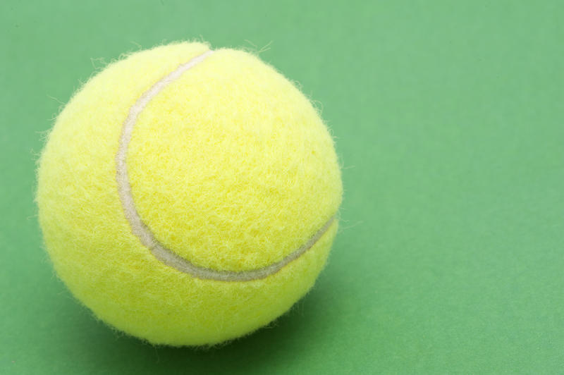 a single tennis ball on a green background