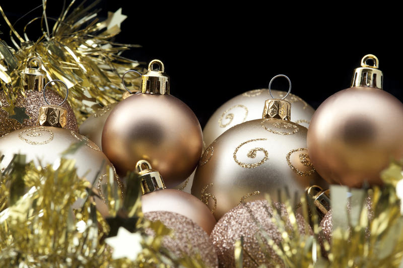 Christmas background with gold Xmas baubles and tinsel over a dark background with copyspace for your seasonal greetings