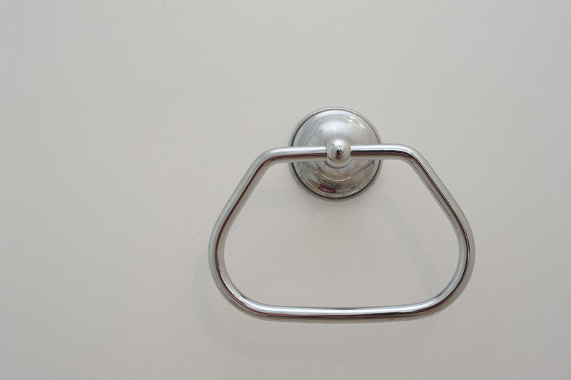 Simple stainless steel towel hanger mounted to the wall in a bathroom interior